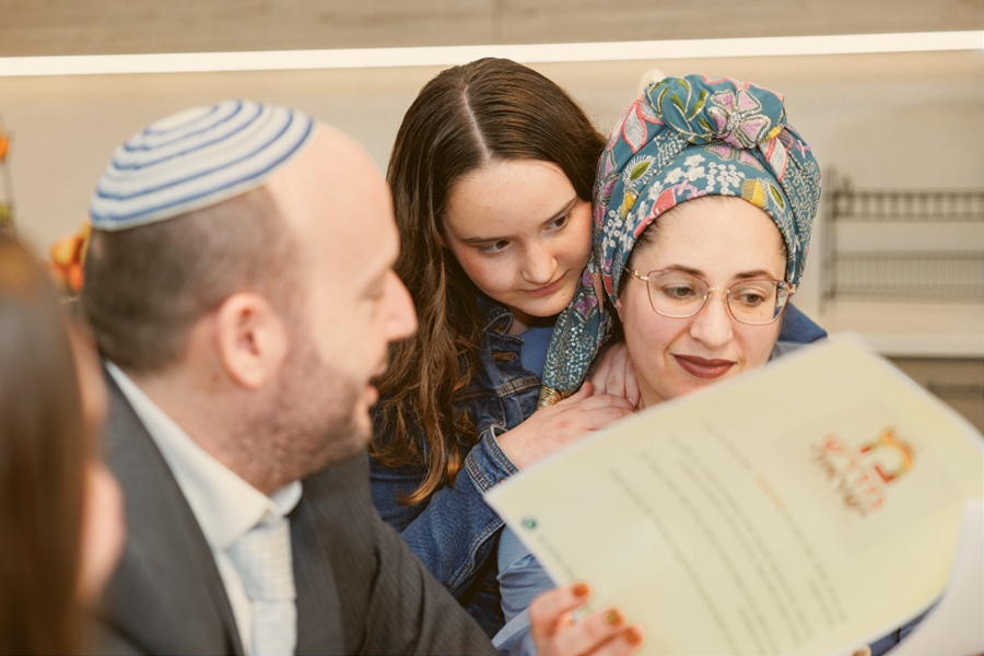 הורים וילדה מתבוננים ביחד בדפי אגדת השבוע